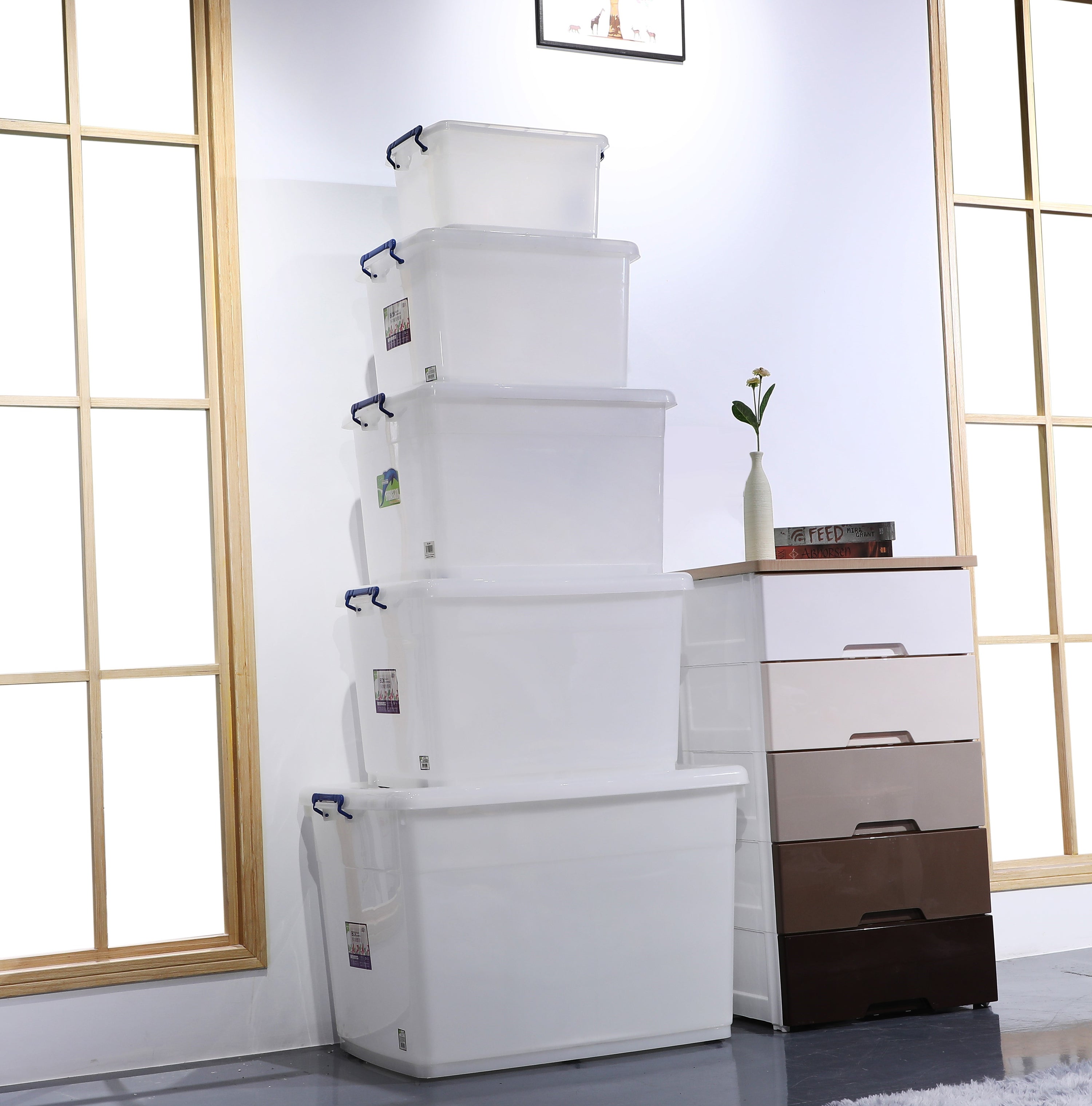Five white stacked storage bins next to a chest of drawers.