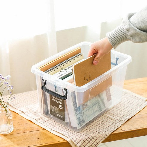 Hand putting notebooks into clear plastic storage box.