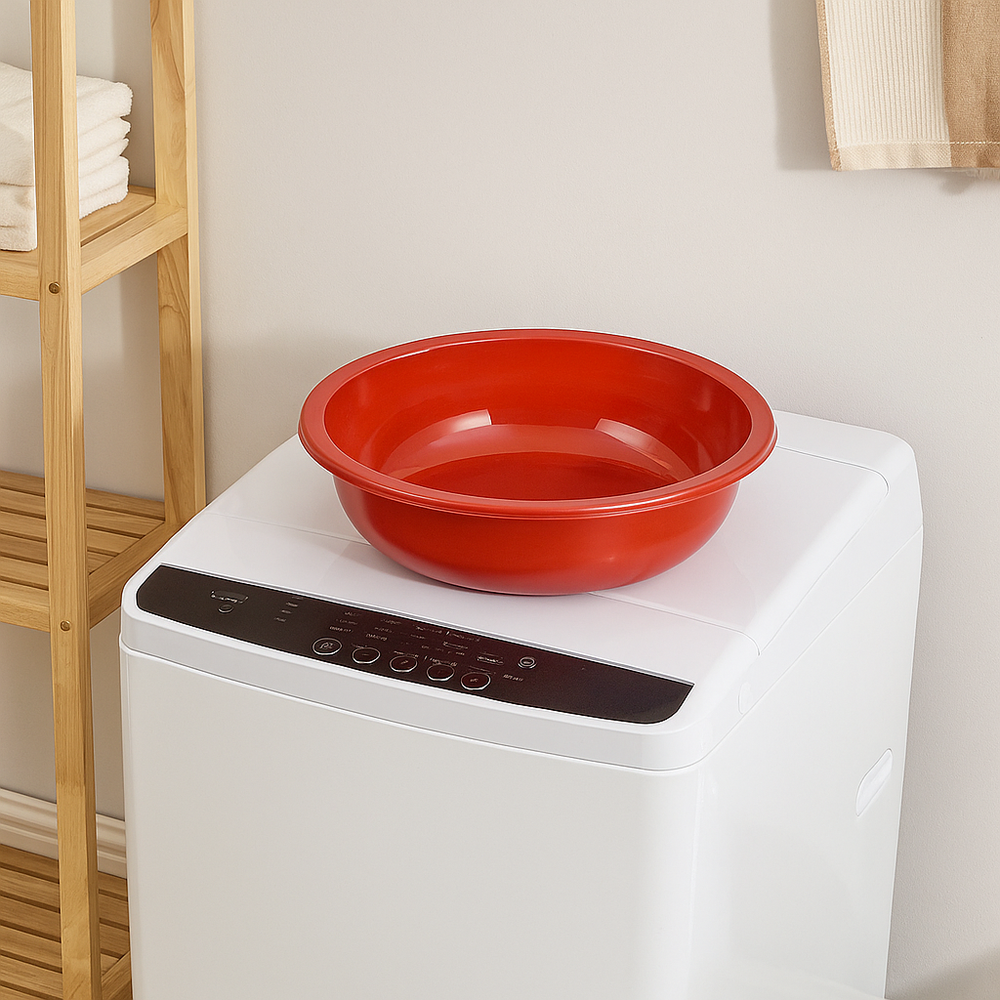 Red plastic Marcolo washbasin on a white washing machine.