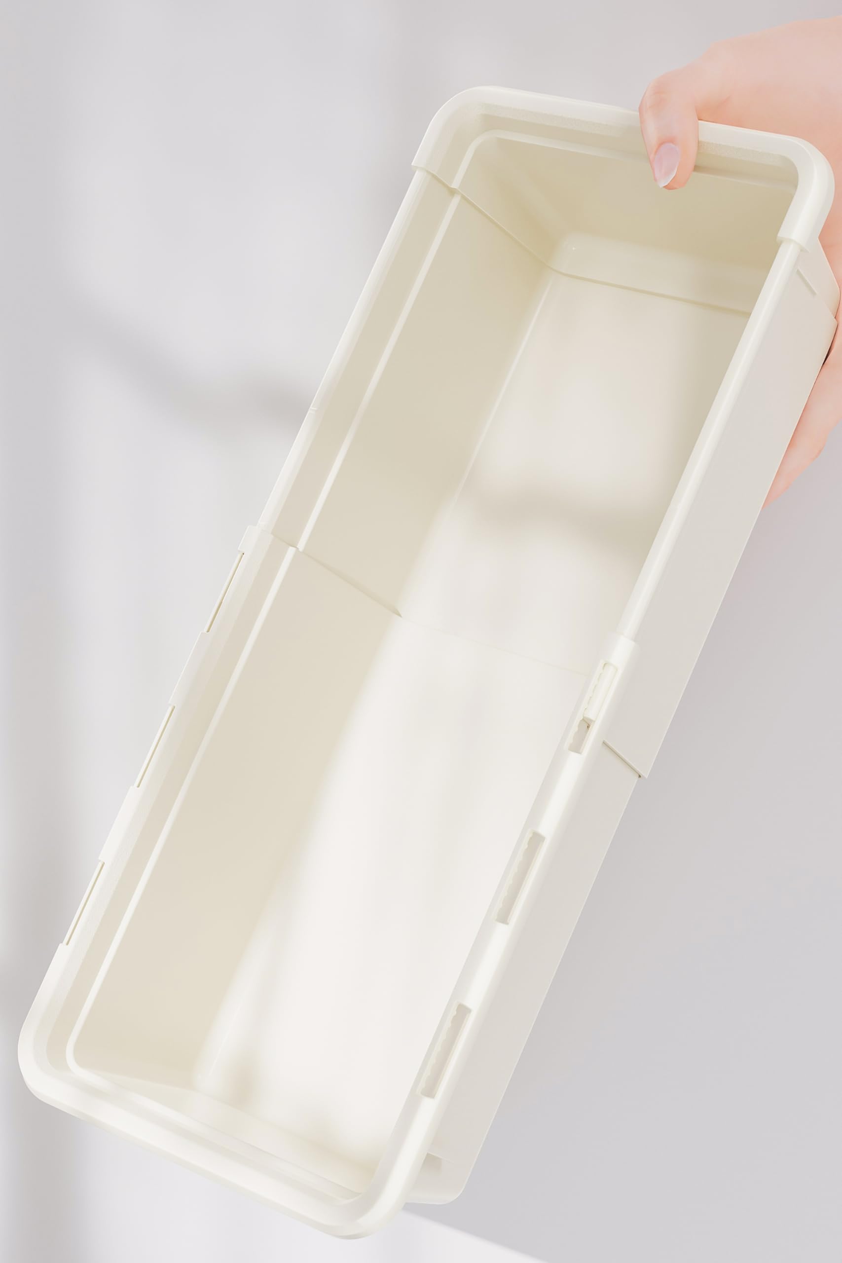 Hand holding a rectangular beige Marcolo plastic storage tray.