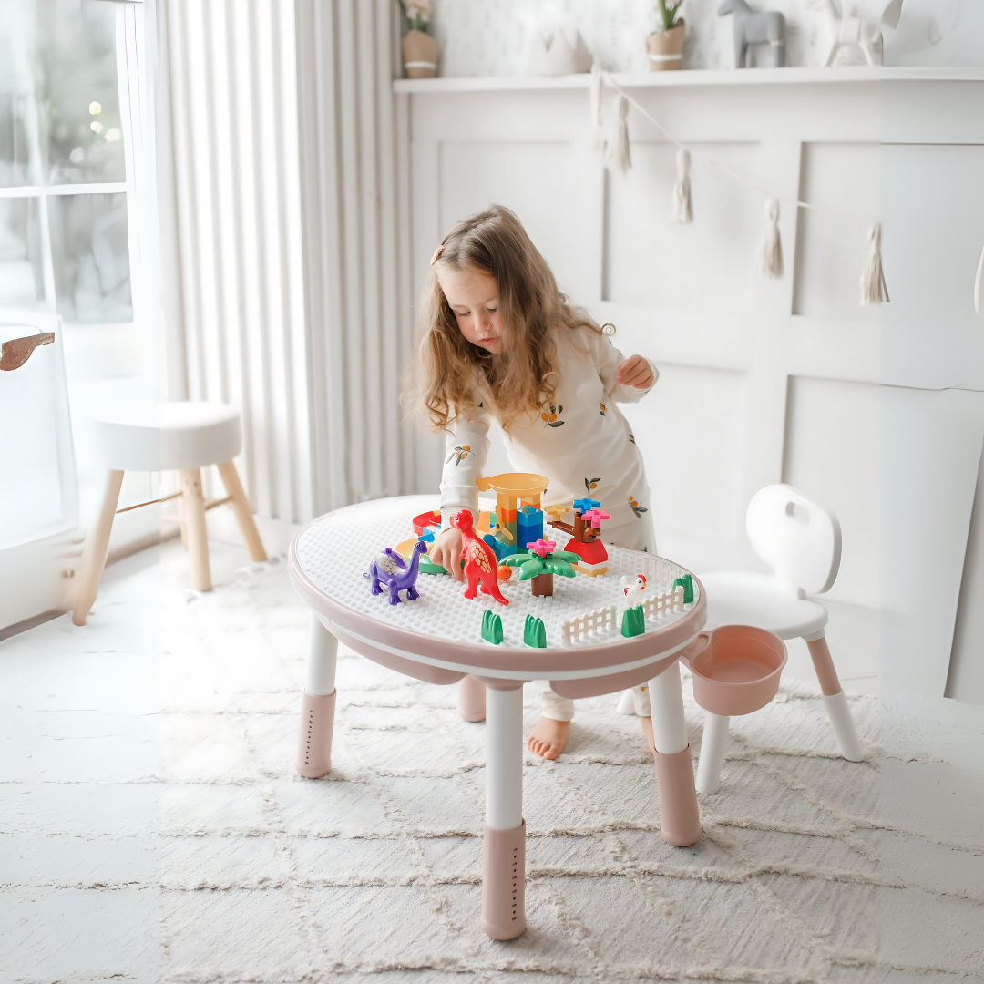 Girl playing with toys at a pink and white Marcolo kids table.