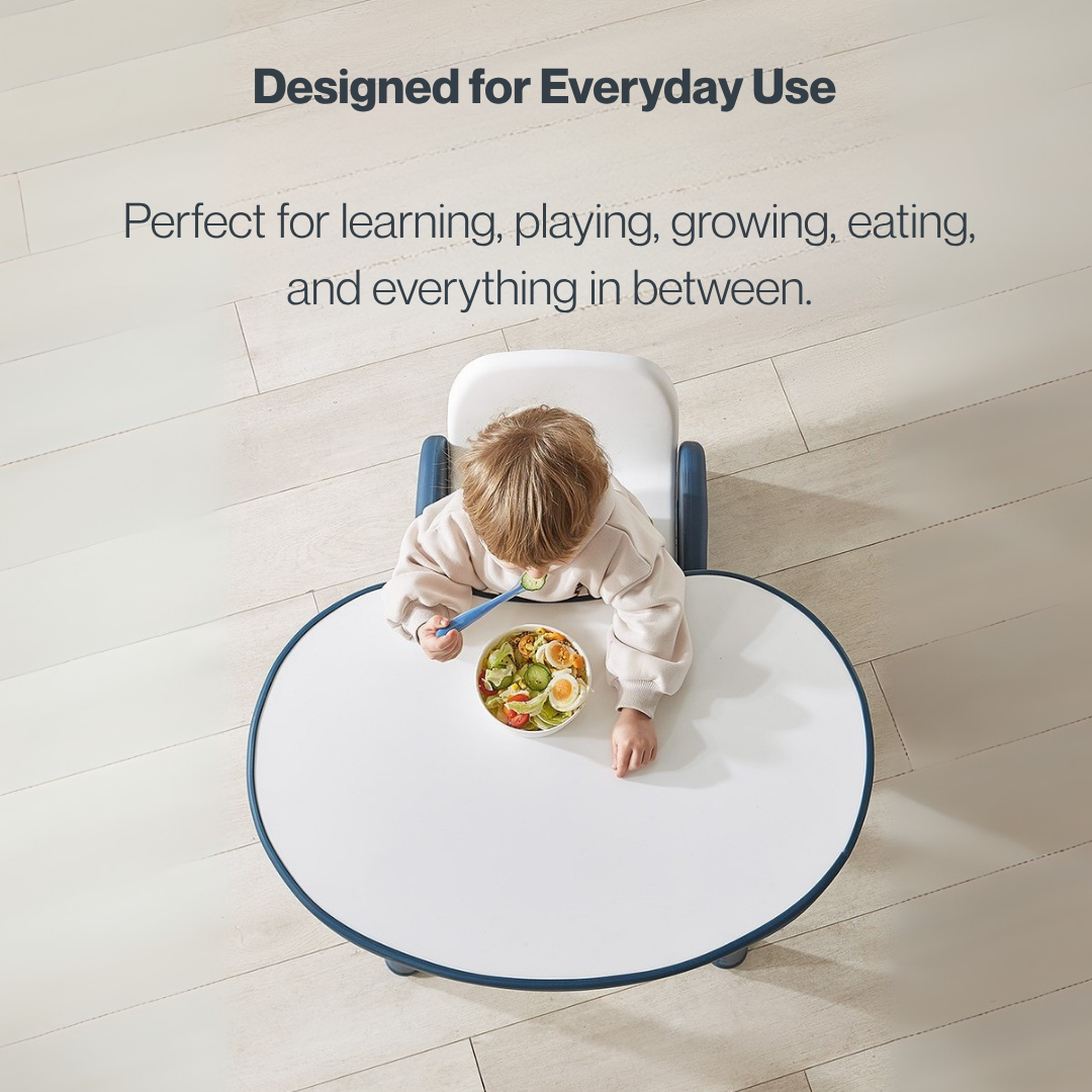 An overhead view of a toddler eating at a white and blue Marcolo round kids' table.
