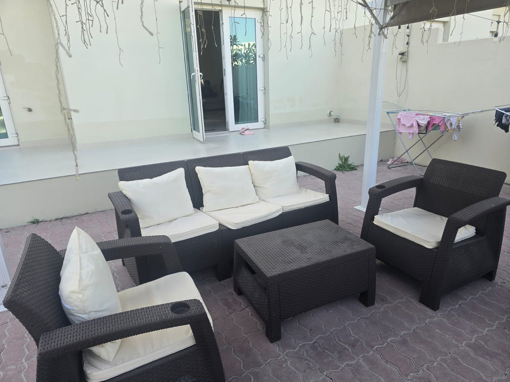 Dark brown Havana rattan-look sofa and armchairs with cream cushions on a customer's shaded terrace