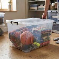 Marcolo 135L clear storage box with wheels, filled with sports gear in a living room