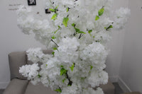 Close-up of white blossoms and green leaves on the Marcolo artificial cherry blossom tree in a living room