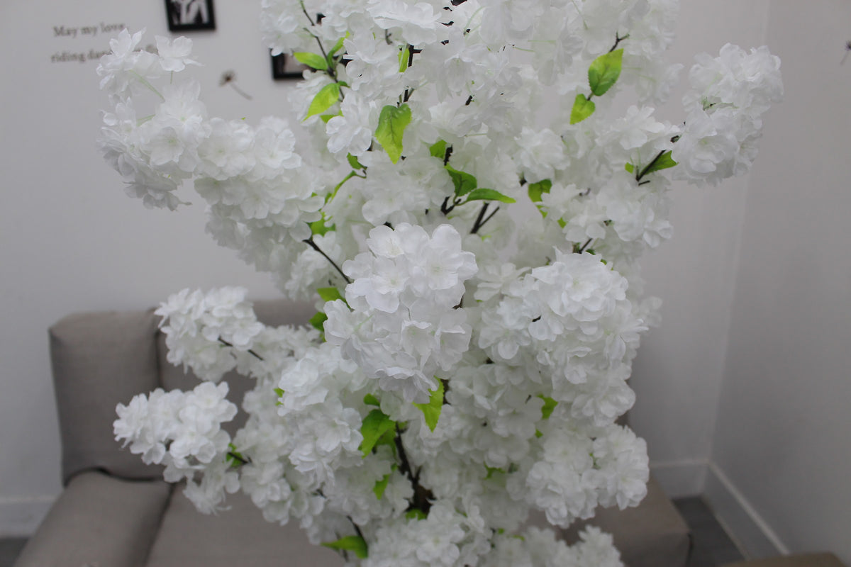 Close-up of white blossoms and green leaves on the Marcolo artificial cherry blossom tree in a living room