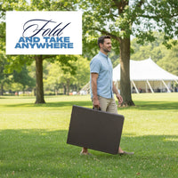 Man carrying the folded Marcolo 6 ft black rattan-style folding table by its handle