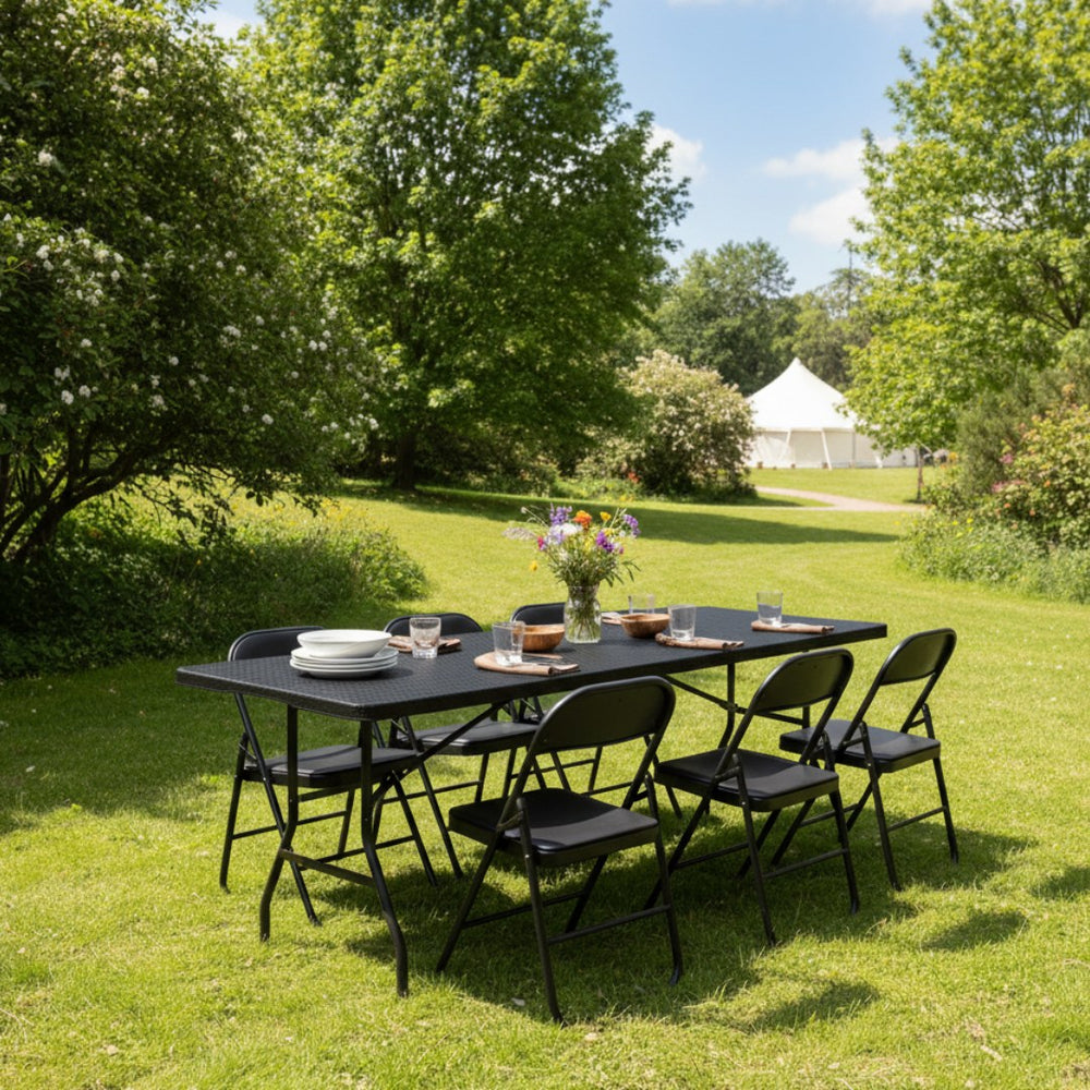 Marcolo 6 ft black rattan-style folding table with chairs in a garden