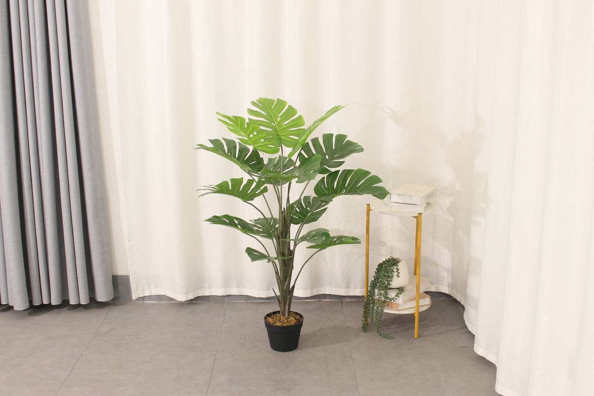 Marcolo 110 cm artificial monstera plant in a room beside a side table