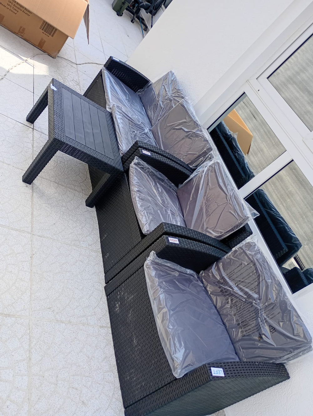 Customer's dark brown Havana rattan-look sofa set unpacked on a tiled balcony