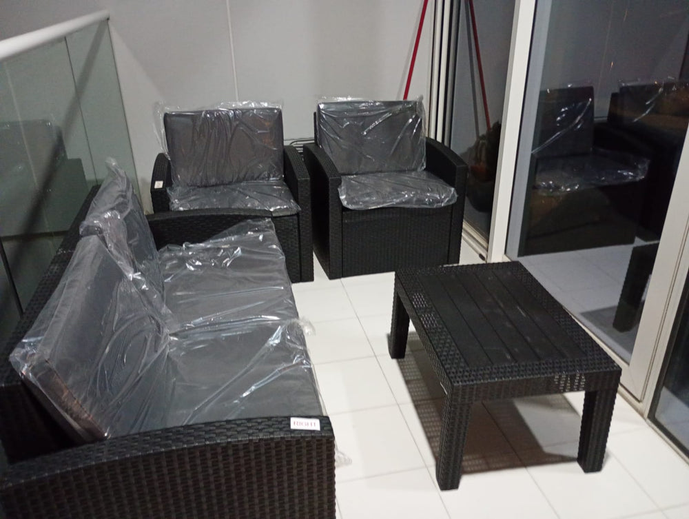 Customer's dark brown Havana rattan-look sofa set in protective wrap on a tiled balcony