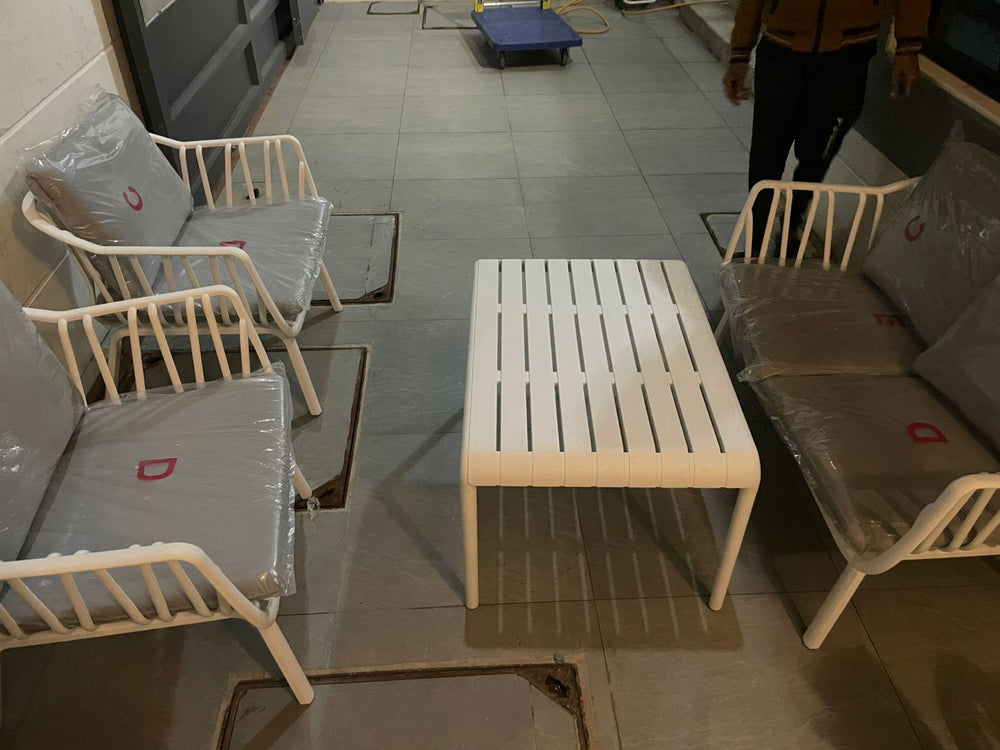 White metal outdoor sofa set with grey cushions and a slatted coffee table being unpacked