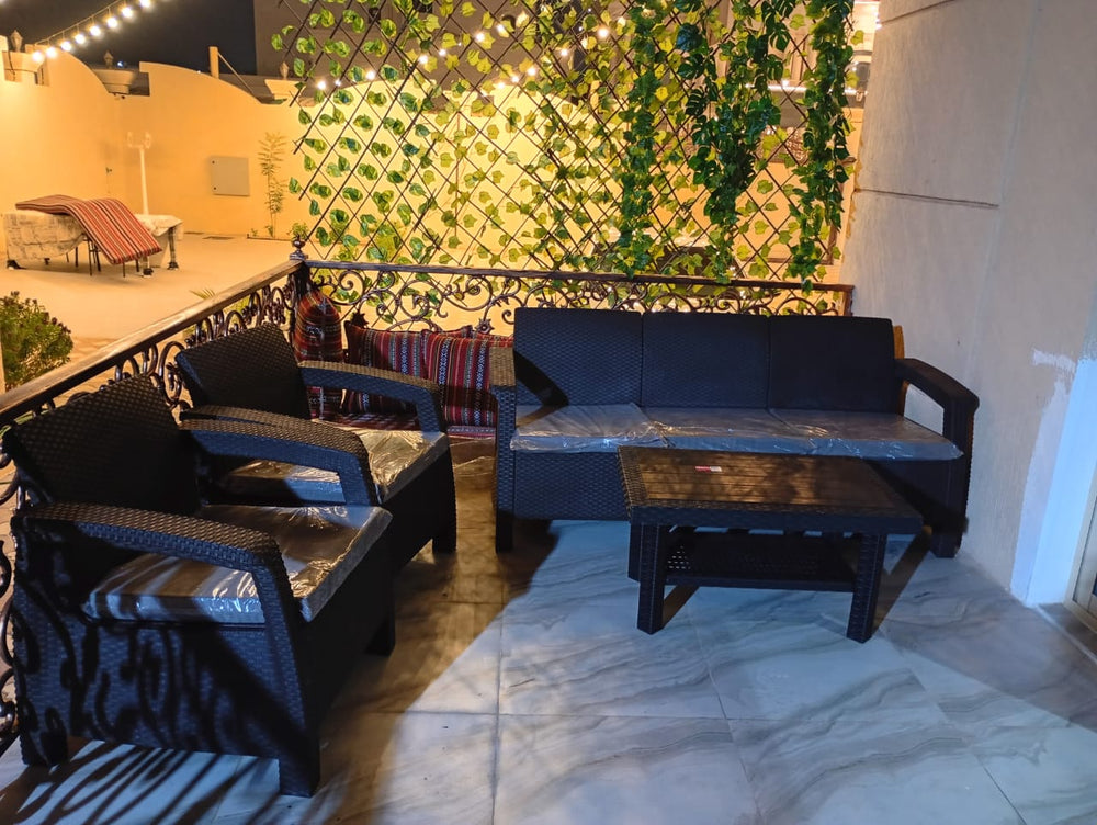 Customer's dark brown Havana rattan-look 5-seater sofa set on a balcony with a green plant wall