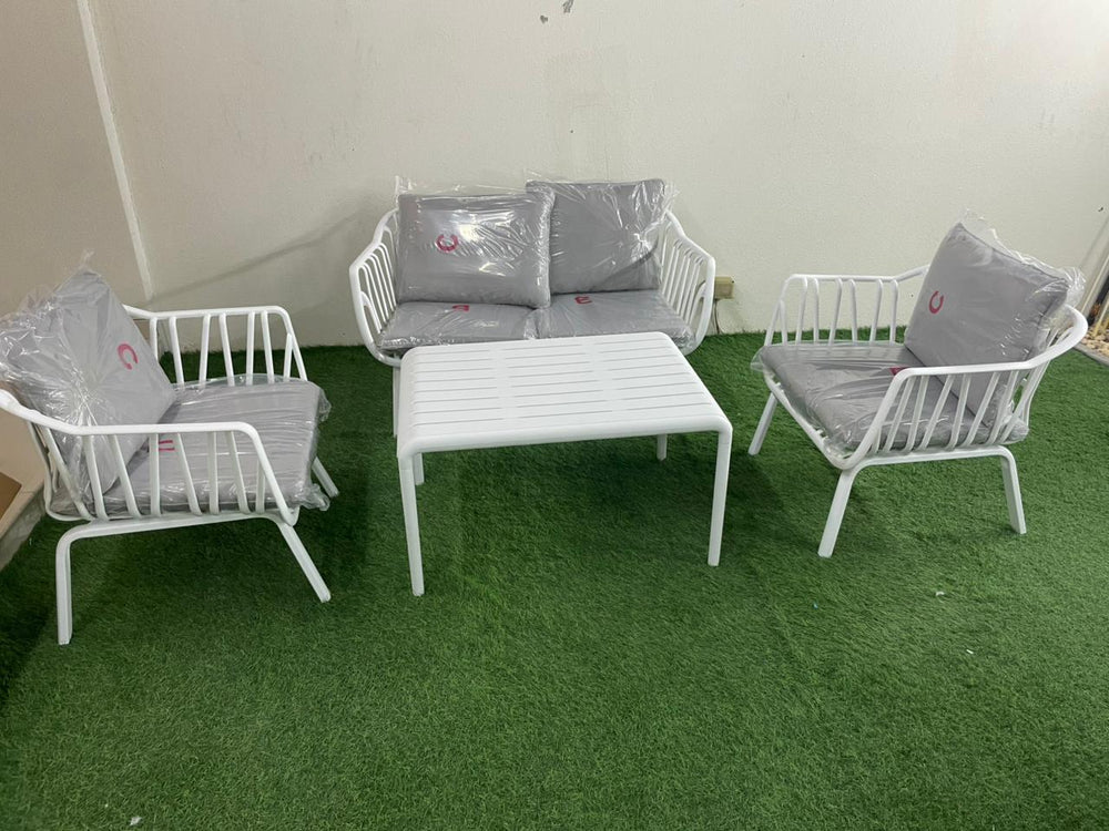White metal 4-seater outdoor set with grey cushions and coffee table on artificial grass