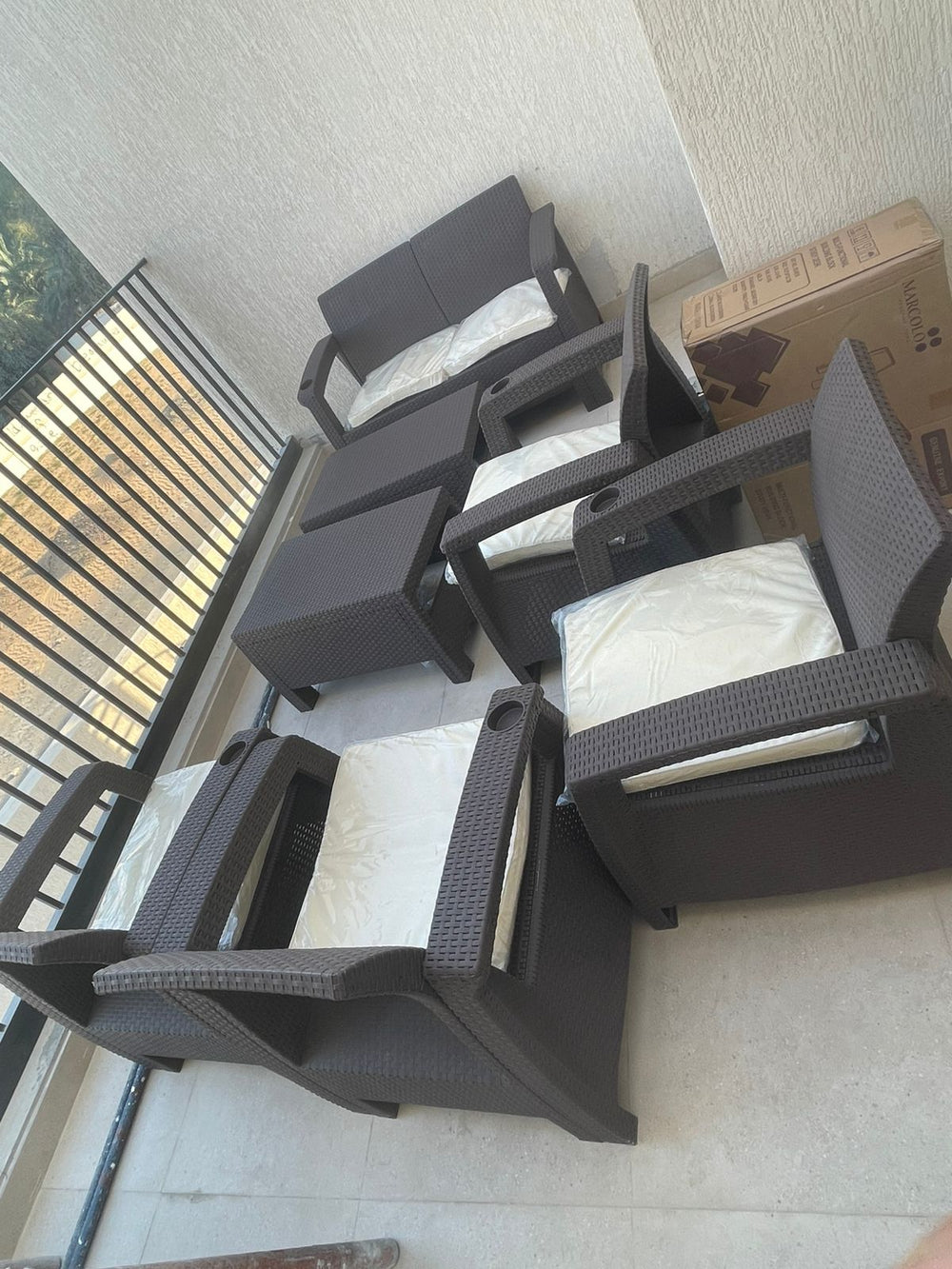 Customer's dark brown Havana rattan-look armchairs with cream cushions on a balcony